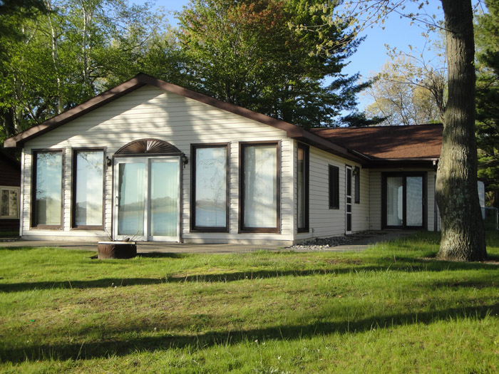 A house with large windows and grass in front of it.