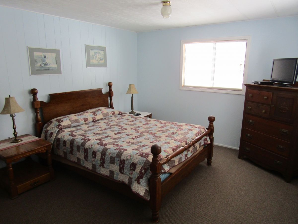 A bedroom with a bed, dresser and window.