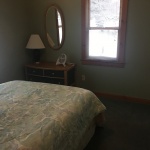 A bedroom with a bed, nightstand and mirror.