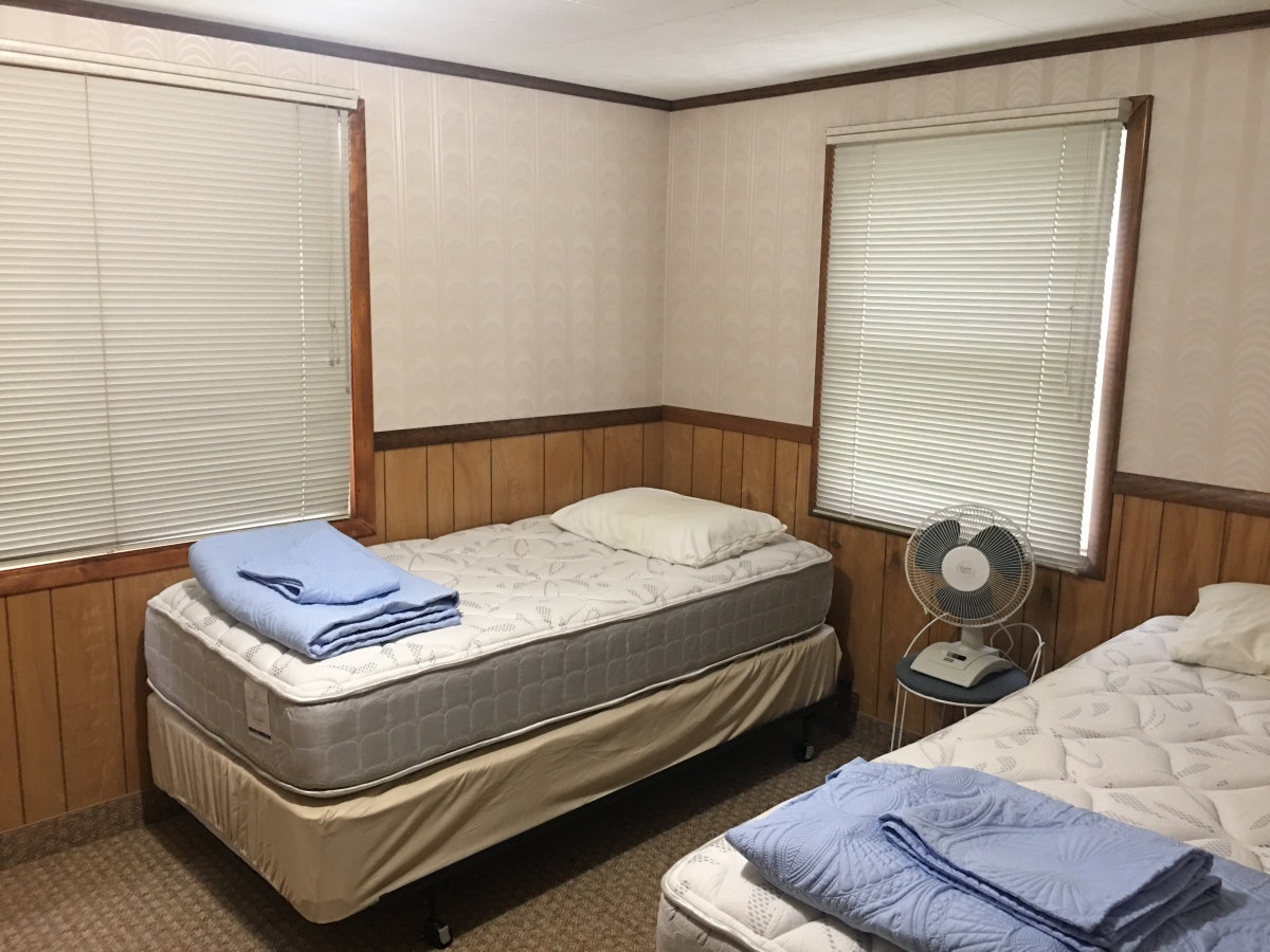A bedroom with two beds and a fan