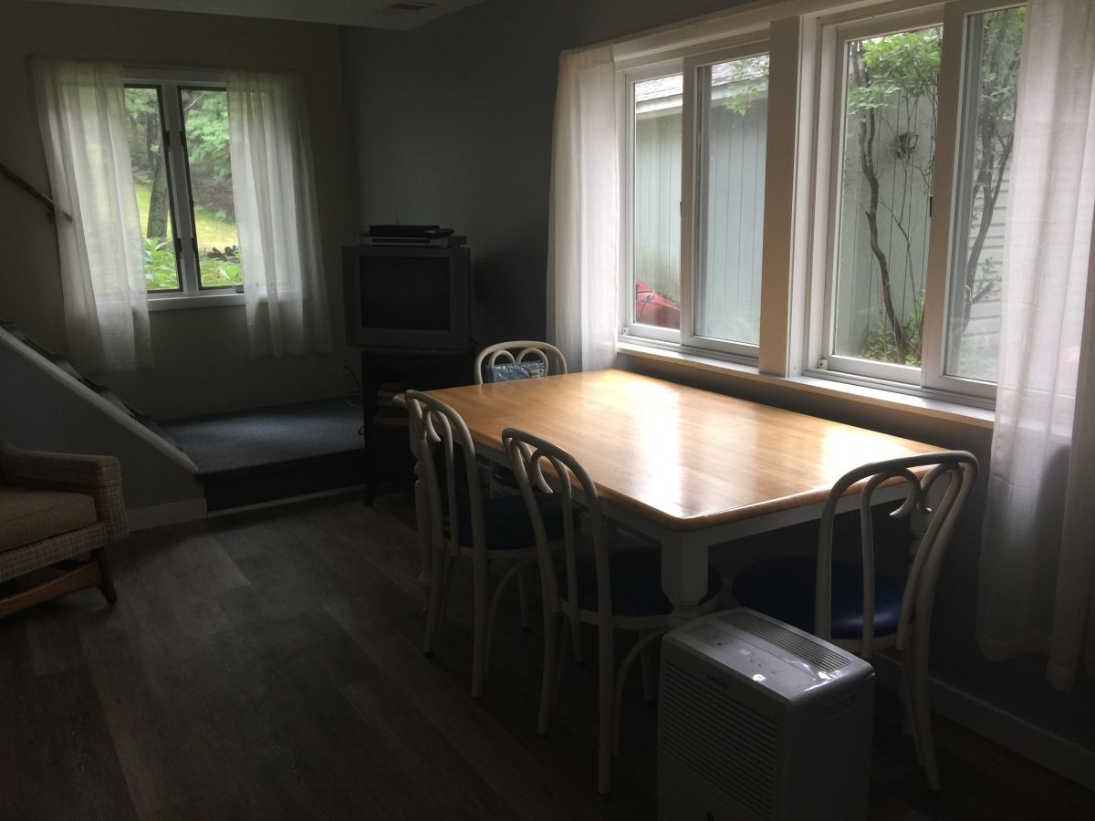 A dining room table with chairs and a couch in the background.