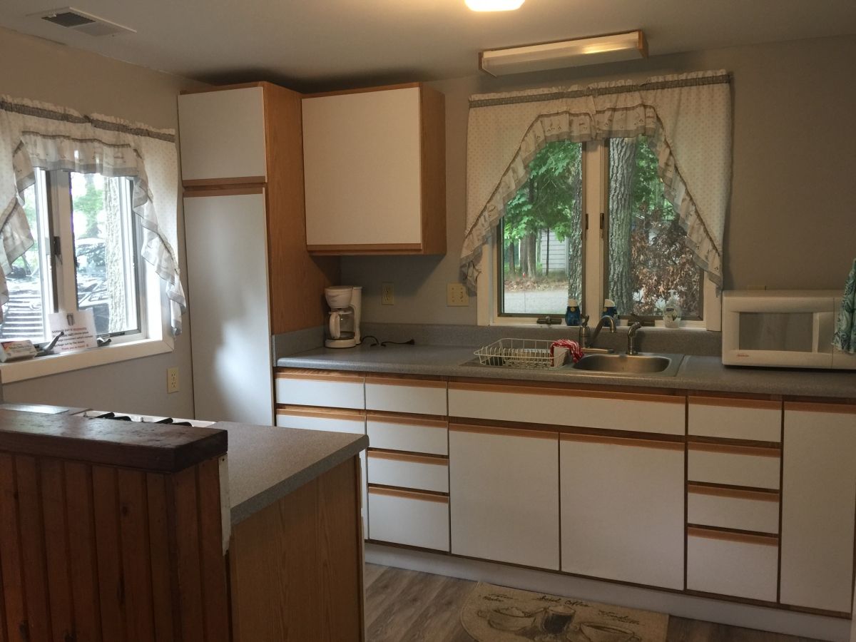 A kitchen with white cabinets and brown wood trim.