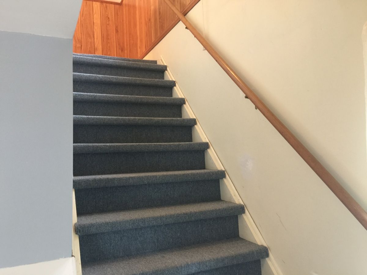 A staircase with blue carpet and wooden handrail.