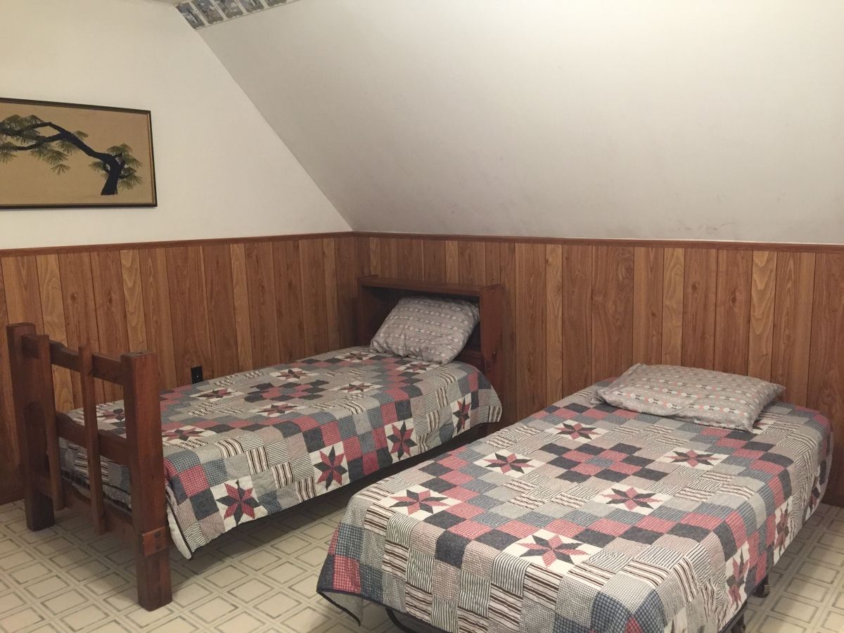 A bedroom with two beds and wooden walls.