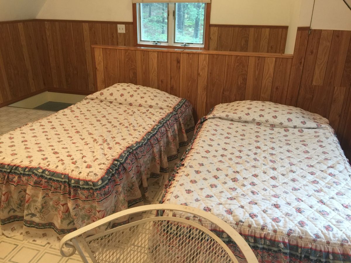 Two beds in a room with wooden walls.