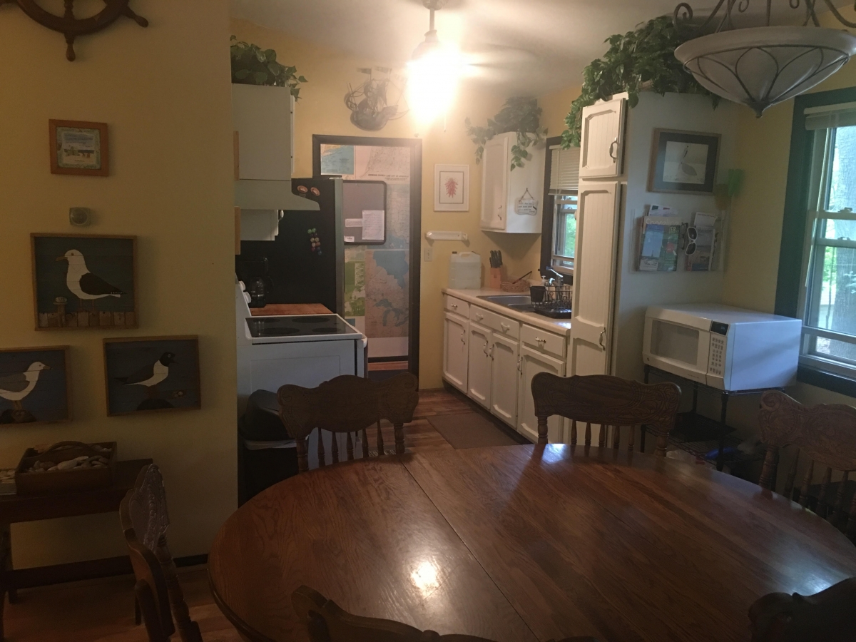 A kitchen with a table and chairs, refrigerator, microwave, oven, and stove.