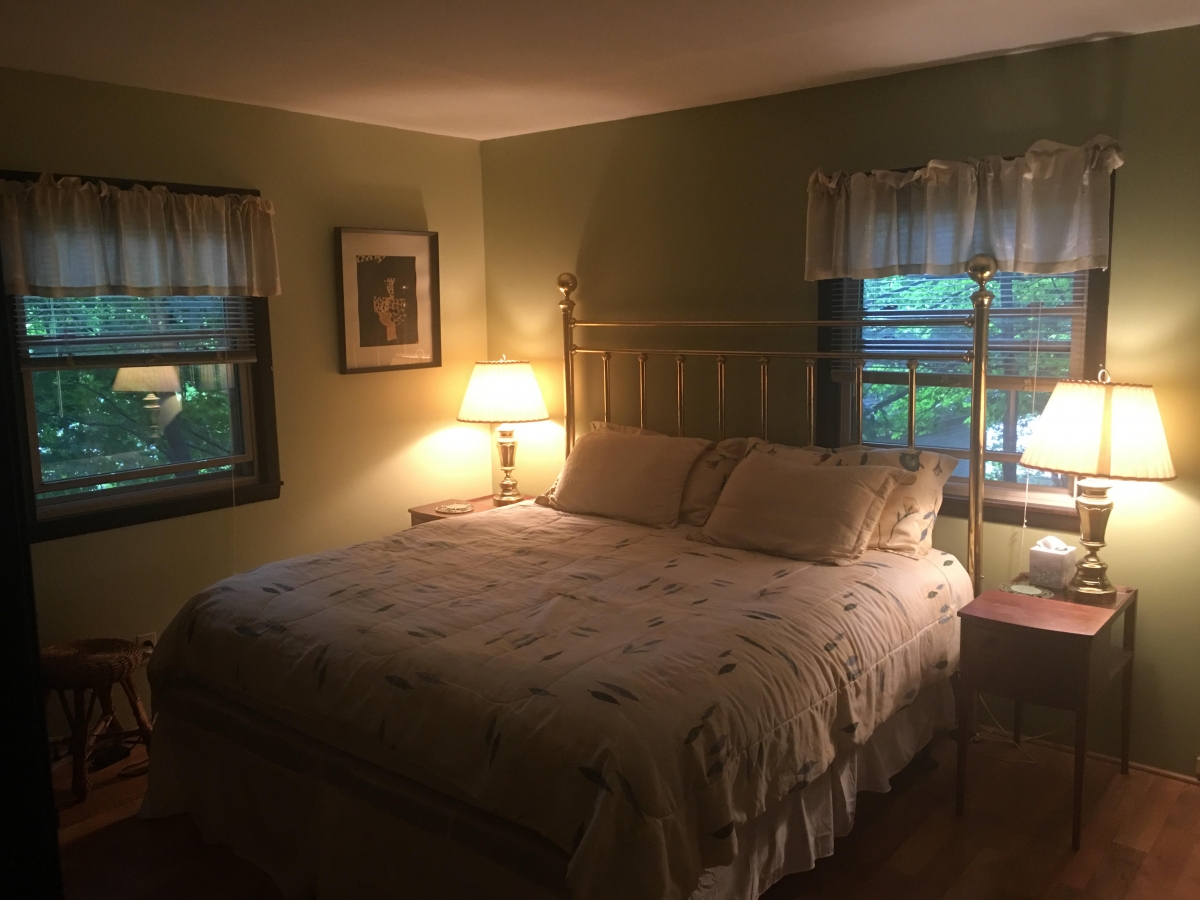 A bedroom with a bed, nightstand and window.