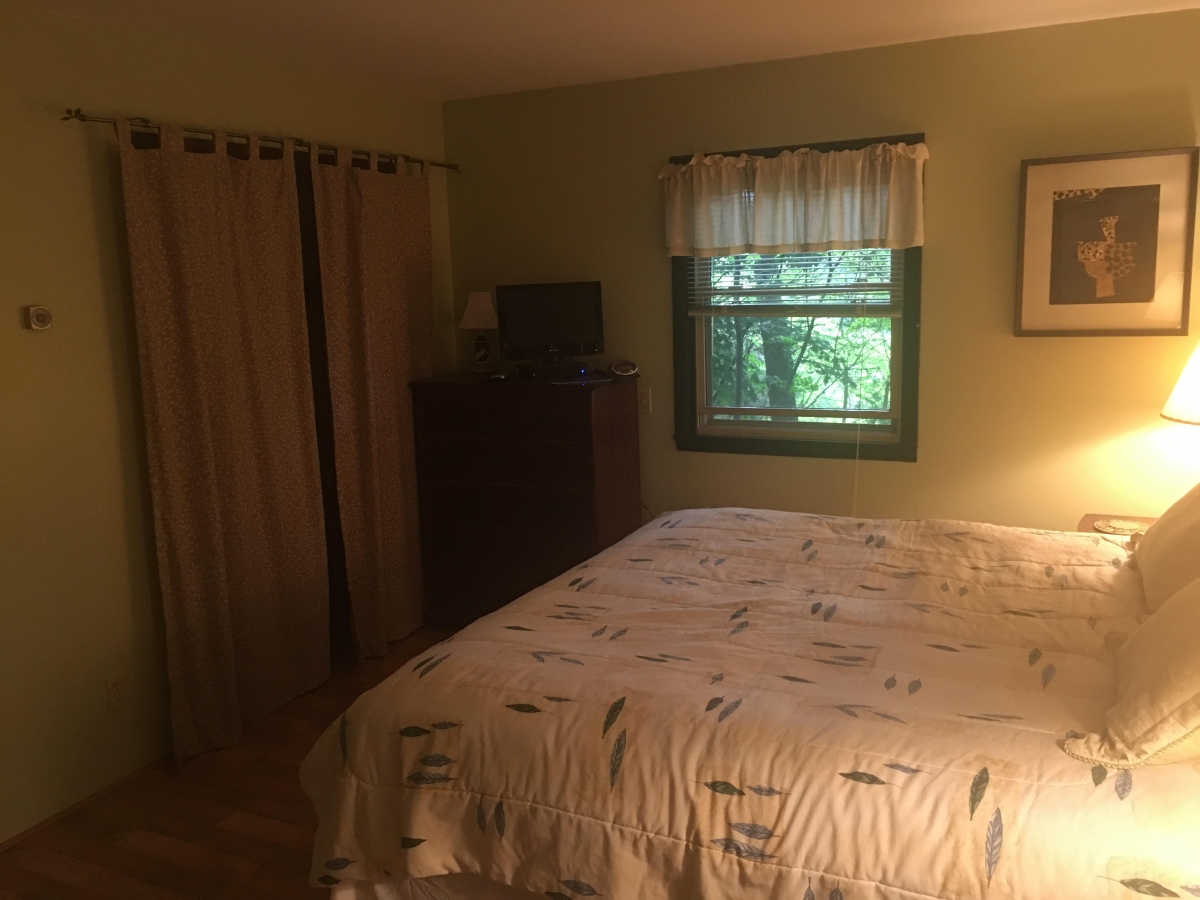 A bedroom with a bed, dresser and window.