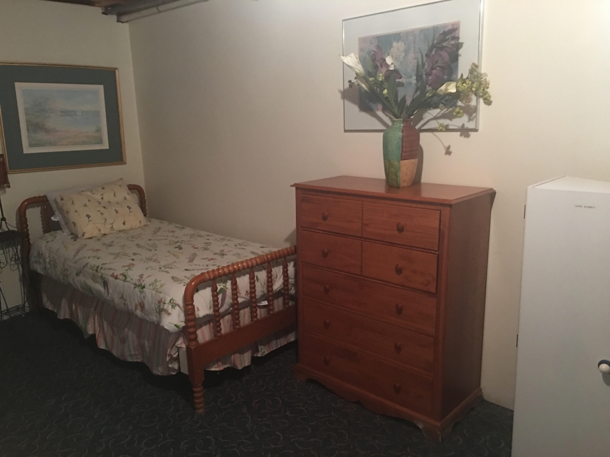 A bedroom with a bed and dresser in it