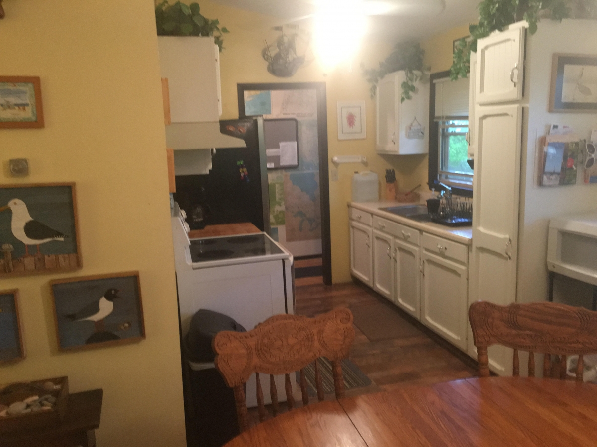 A kitchen with white cabinets and wooden floors.