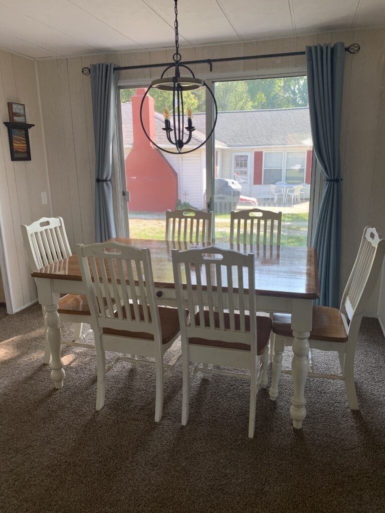 A dining room table with six chairs and a chandelier.