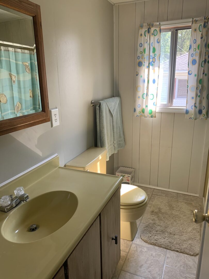A bathroom with a sink, toilet and mirror.