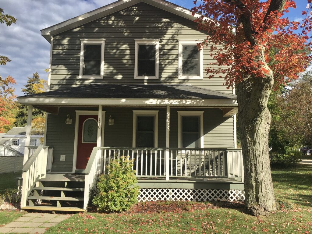 A house with a porch and steps leading to the front door.