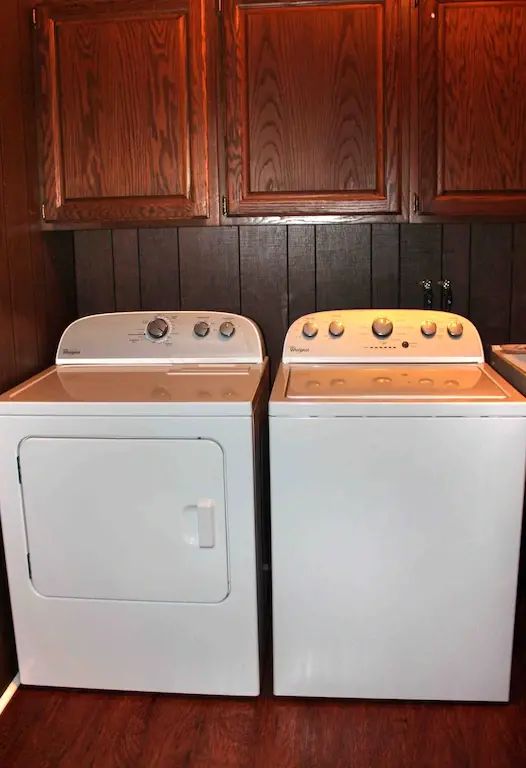 A couple of white appliances sitting in front of wooden cabinets.