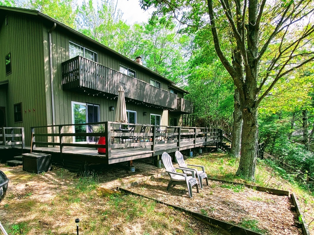 A wooden deck with chairs and trees in the background.