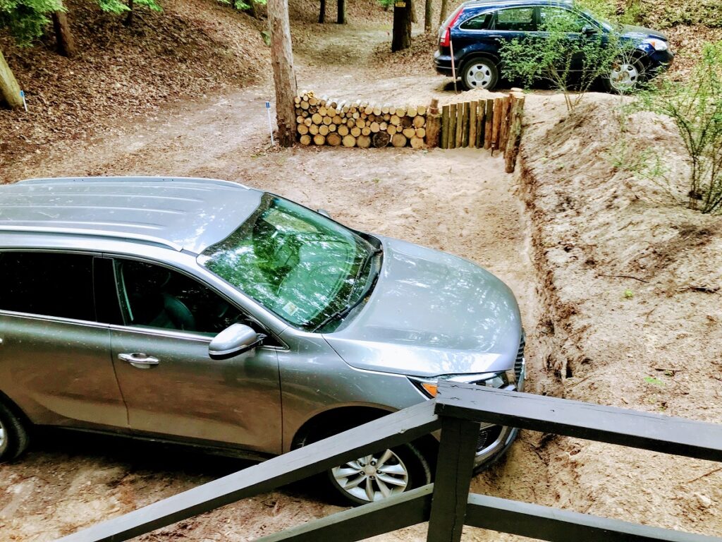 A silver car parked on top of a dirt road.