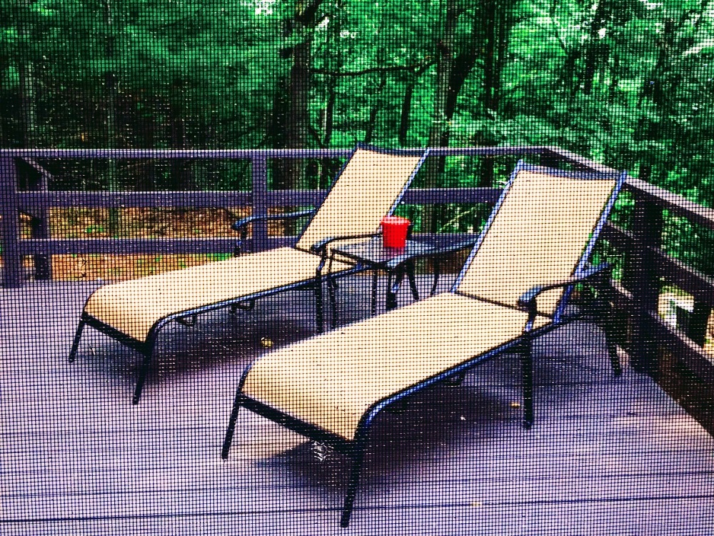 A deck with two lounge chairs and a table.