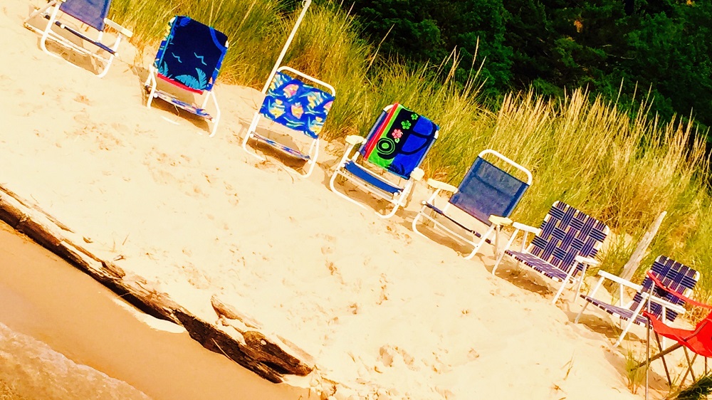 A row of lawn chairs sitting on top of the sand.