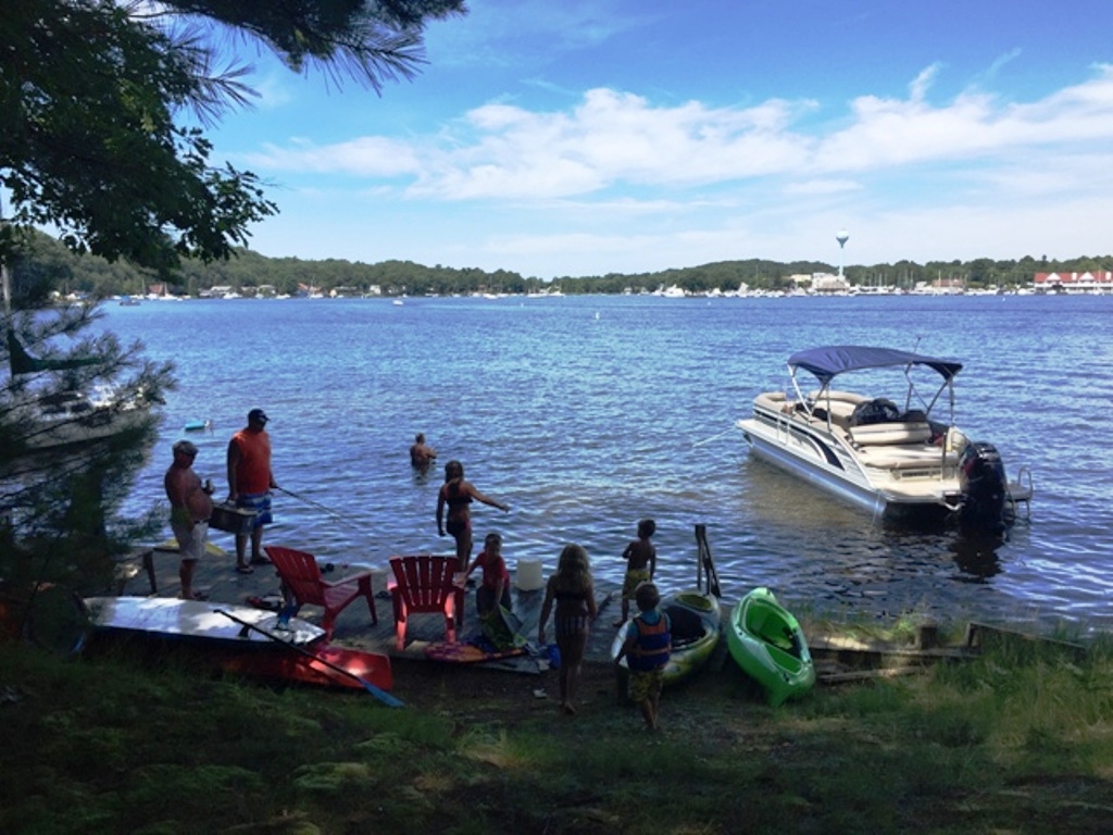 A group of people standing on the shore near boats.