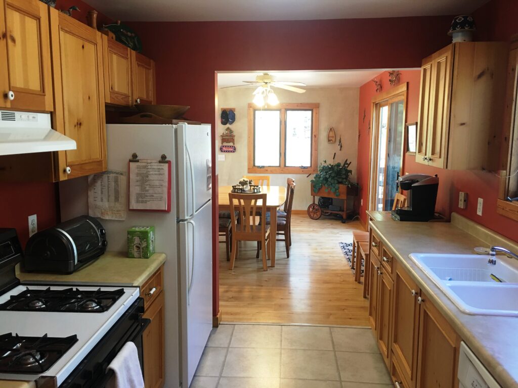 A kitchen with a stove, refrigerator and dining room table.