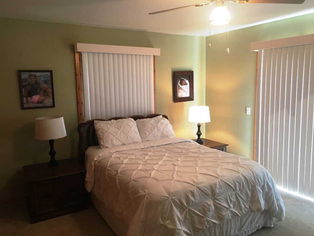 A bedroom with a bed, two lamps and a window.