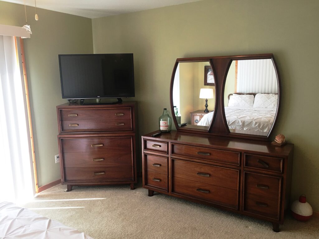 A dresser and mirror in the corner of a room.