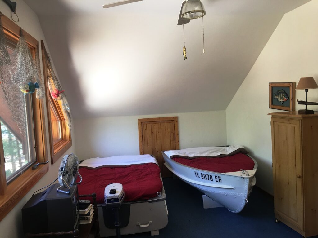 A room with two beds and a boat in it.