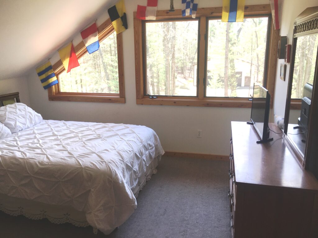 A bedroom with two windows and a bed