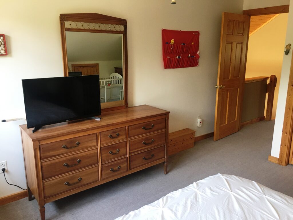 A bedroom with a dresser and tv in it