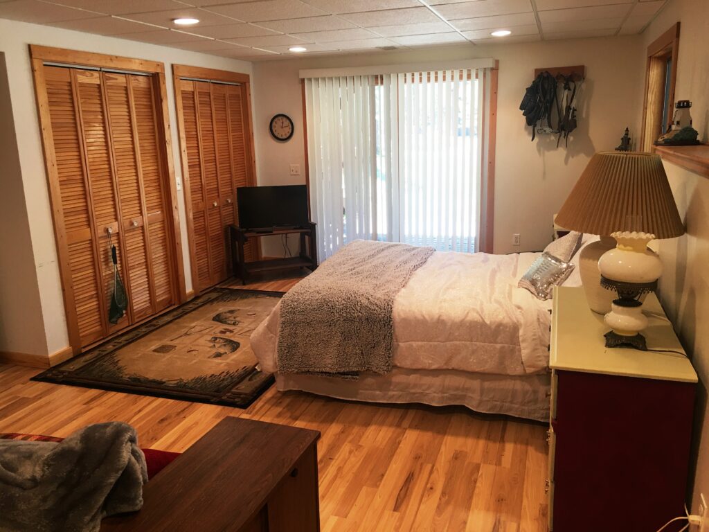 A bedroom with a bed, dresser and tv.