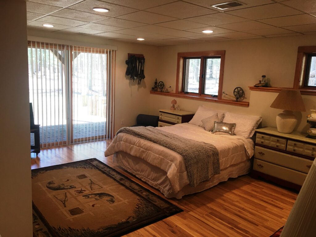 A bedroom with a bed, dresser and window.