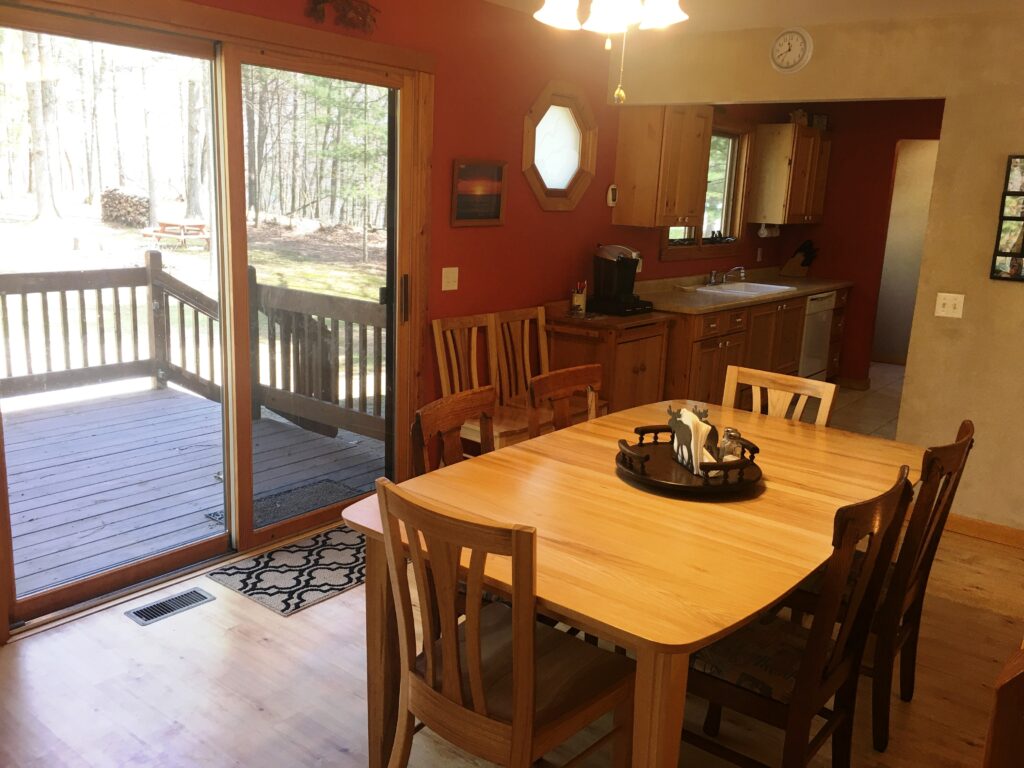 A dining room table with chairs and a sliding glass door.