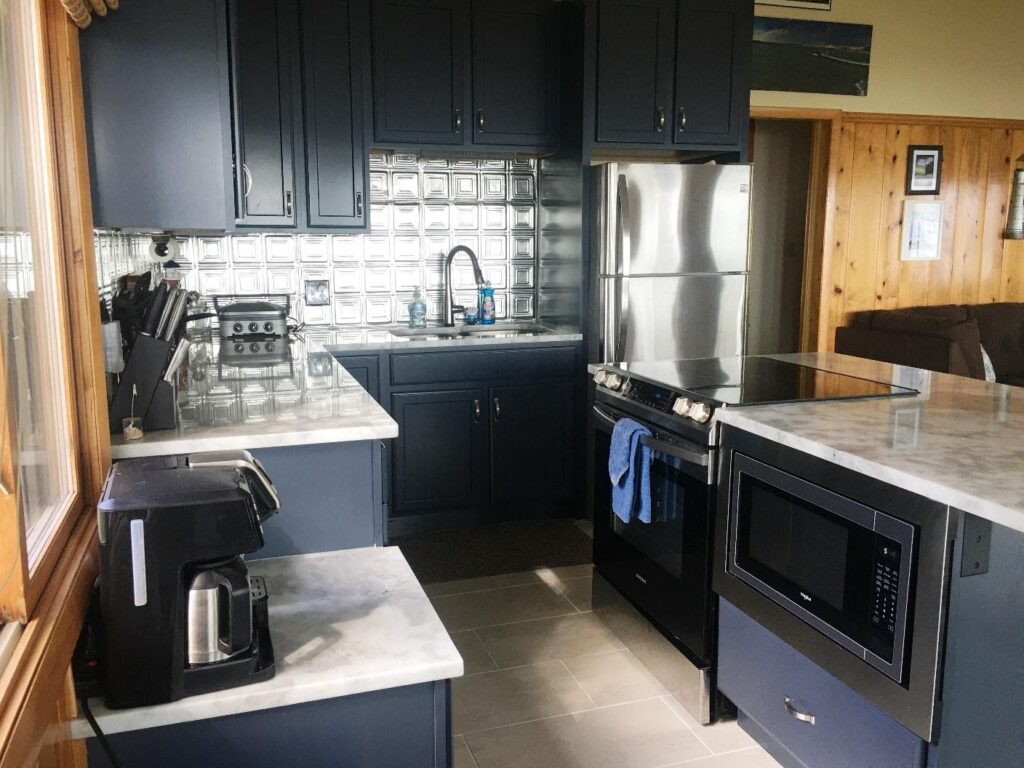A kitchen with black cabinets and stainless steel appliances.