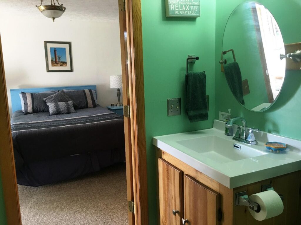 A bathroom with green walls and a bed in the background.