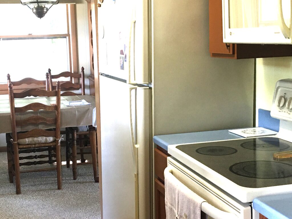 A kitchen with a stove, refrigerator and table.