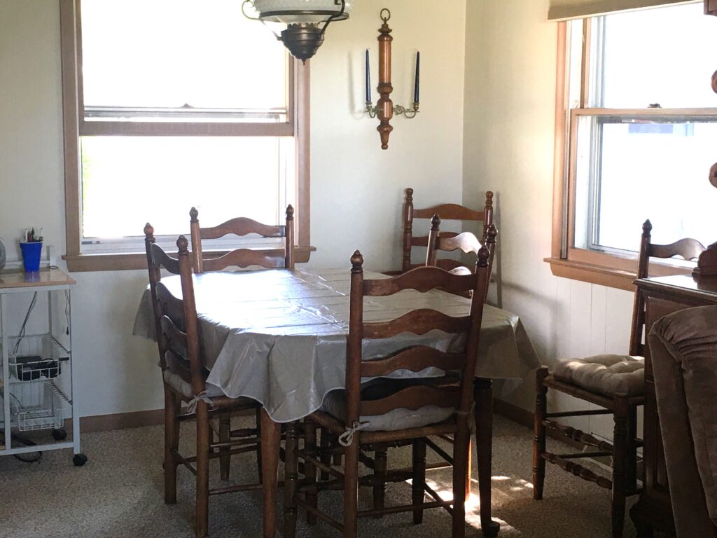 A dining room table with four chairs and a chandelier.