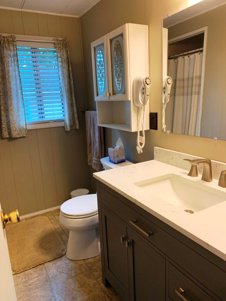 A bathroom with a sink, toilet and mirror.