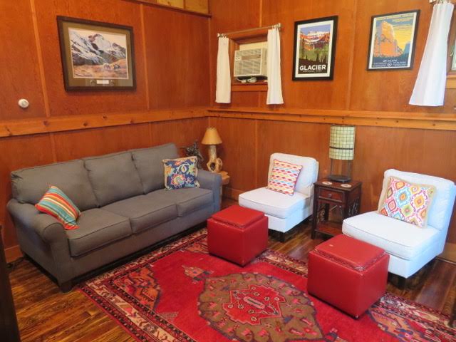 A living room with wood paneled walls and red carpet.
