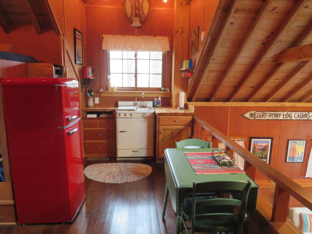 A kitchen with a table, chairs and refrigerator.