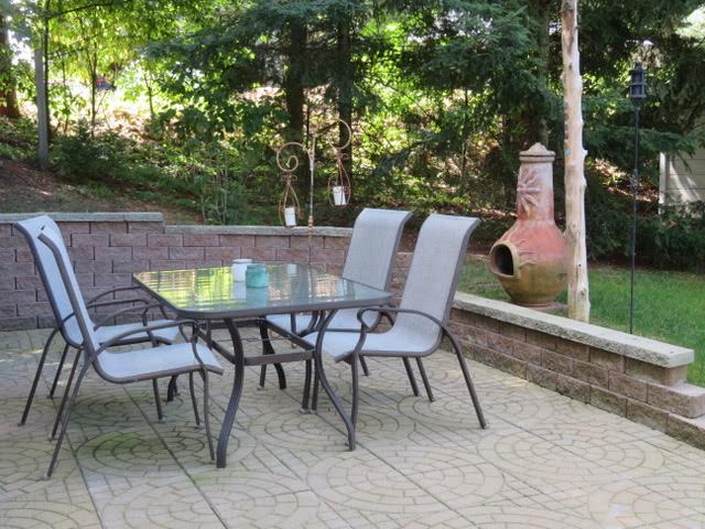 A patio table and chairs on the side of a brick wall.