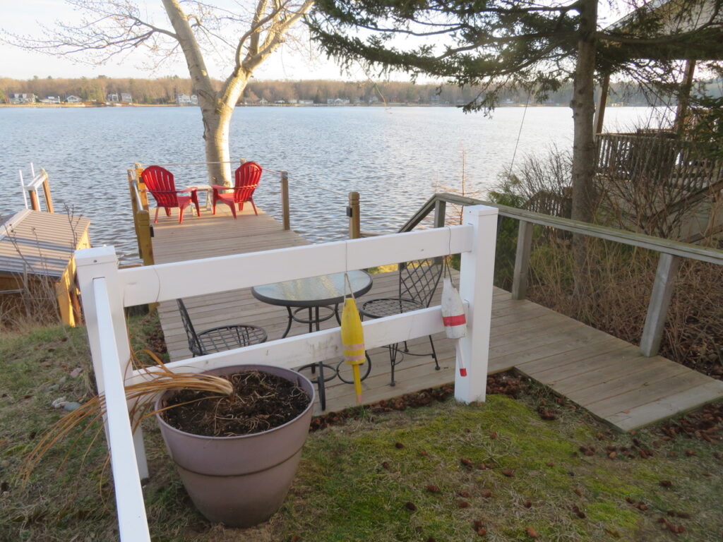 A deck with chairs and tables overlooking the water.