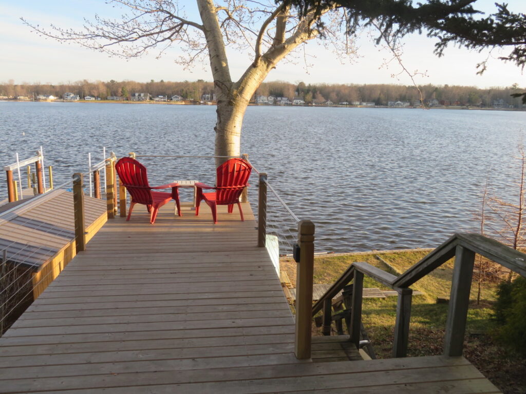 A deck with chairs and tables overlooking the water.
