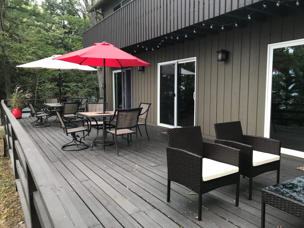 A patio with chairs and tables on the back deck.