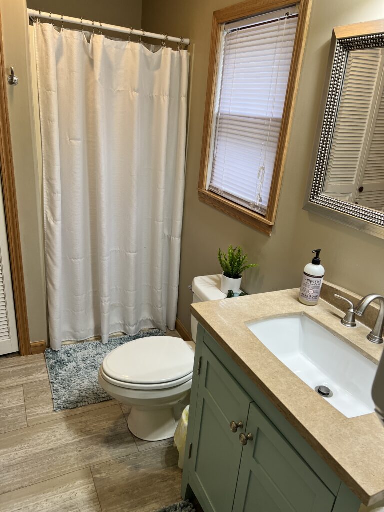 A bathroom with a toilet, sink and shower.