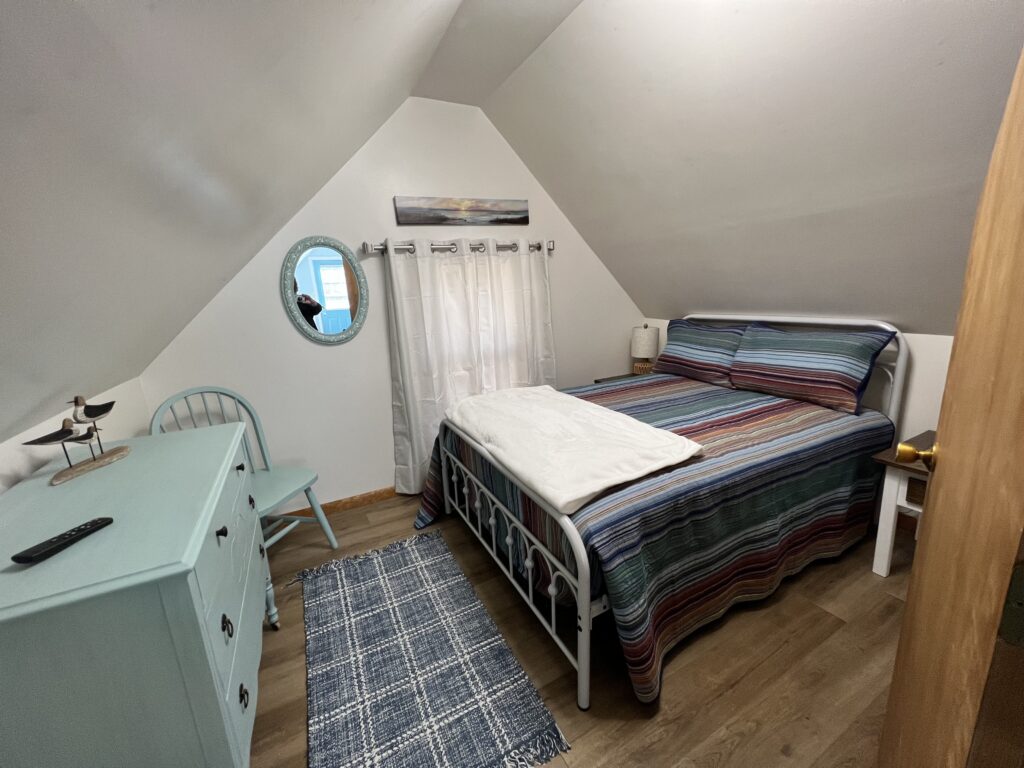 A bedroom with a bed, dresser and mirror.