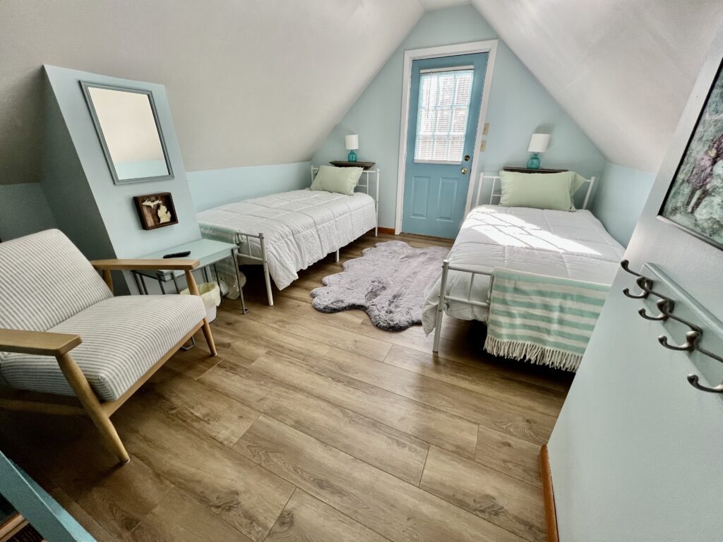 A bedroom with two beds and a door.