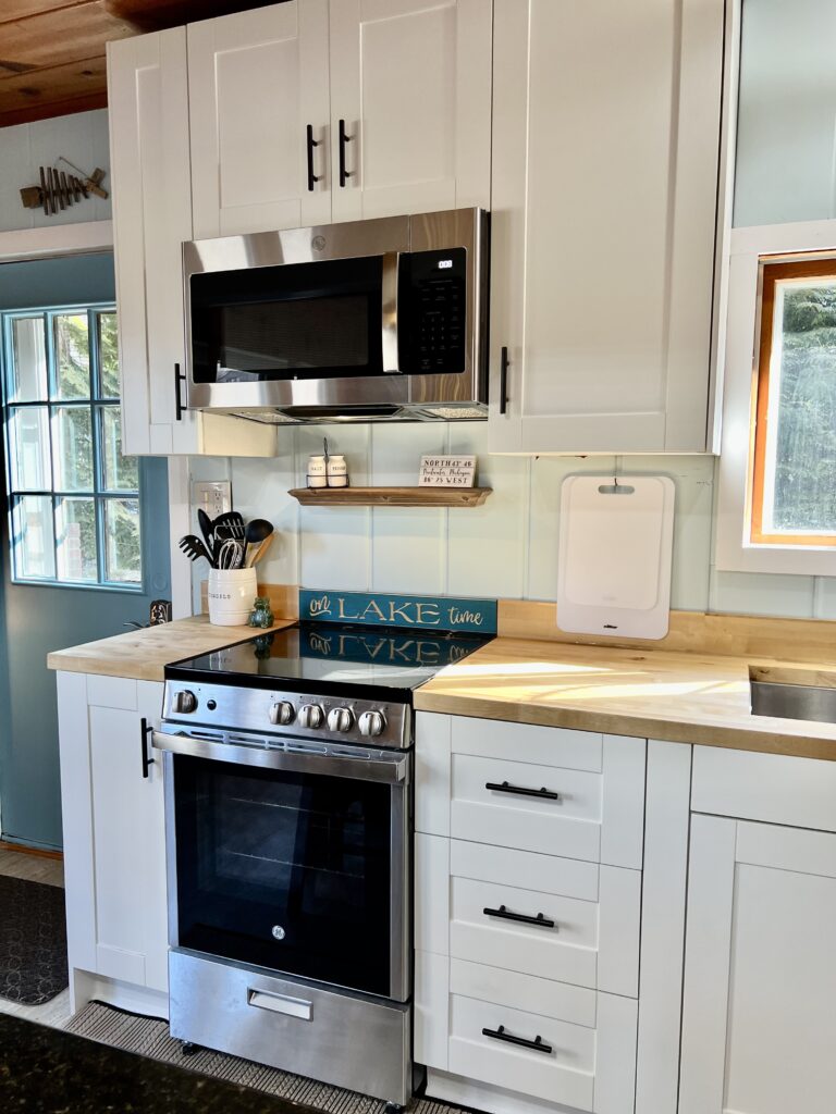 A kitchen with white cabinets and black oven.