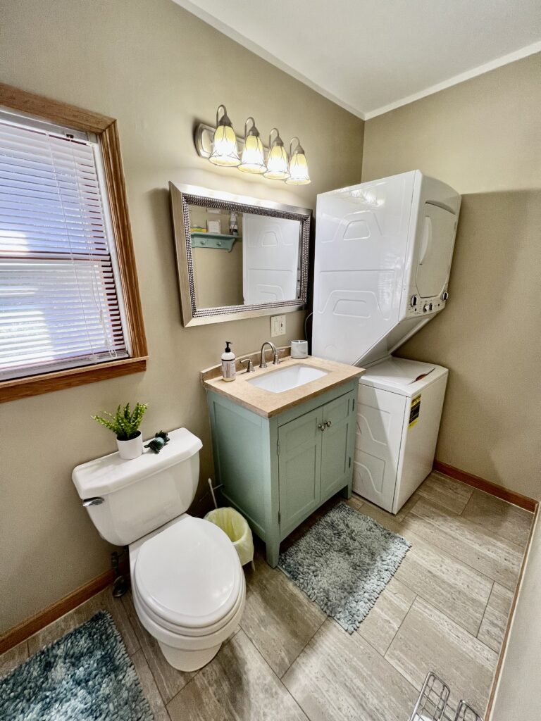 A bathroom with a toilet, sink and mirror.