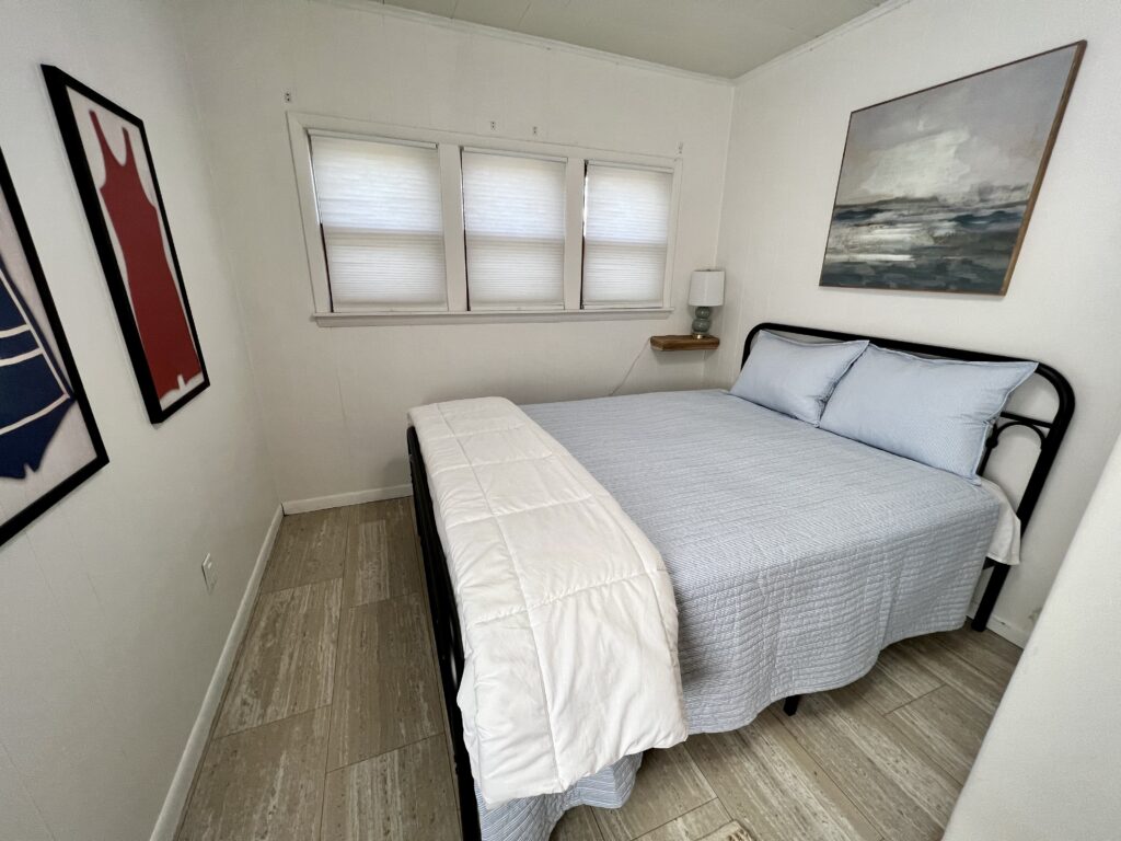 A bedroom with a bed, nightstand and window.