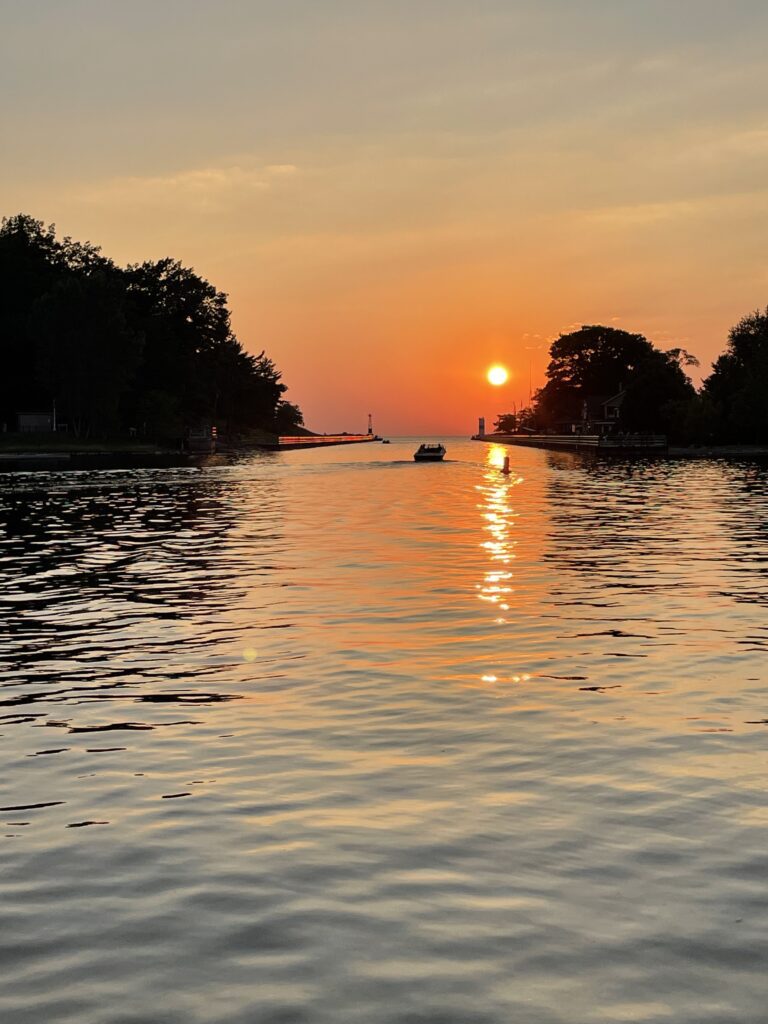 A boat is traveling down the river at sunset.